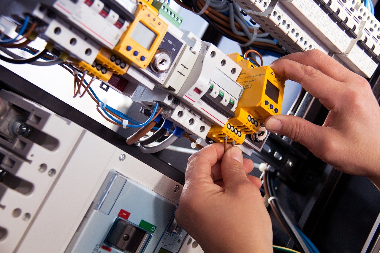 Zwei Hände montieren elektronische Komponenten und Verdrahtung in einem Schaltschrank zur Darstellung der präzisen Baugruppenmontage